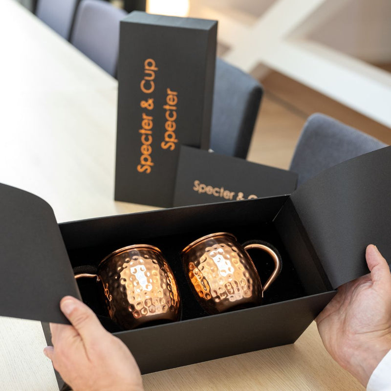 Geöffnete Premiumbox mit zwei Moscow Mule Kupferbechern Specter, von zwei Händen gehalten